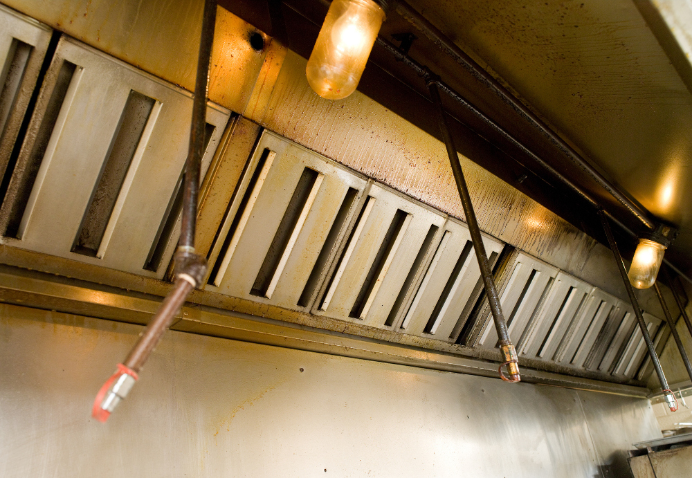 Greasy restaurant kitchen hood showing why full kitchen exhaust system cleaning is needed